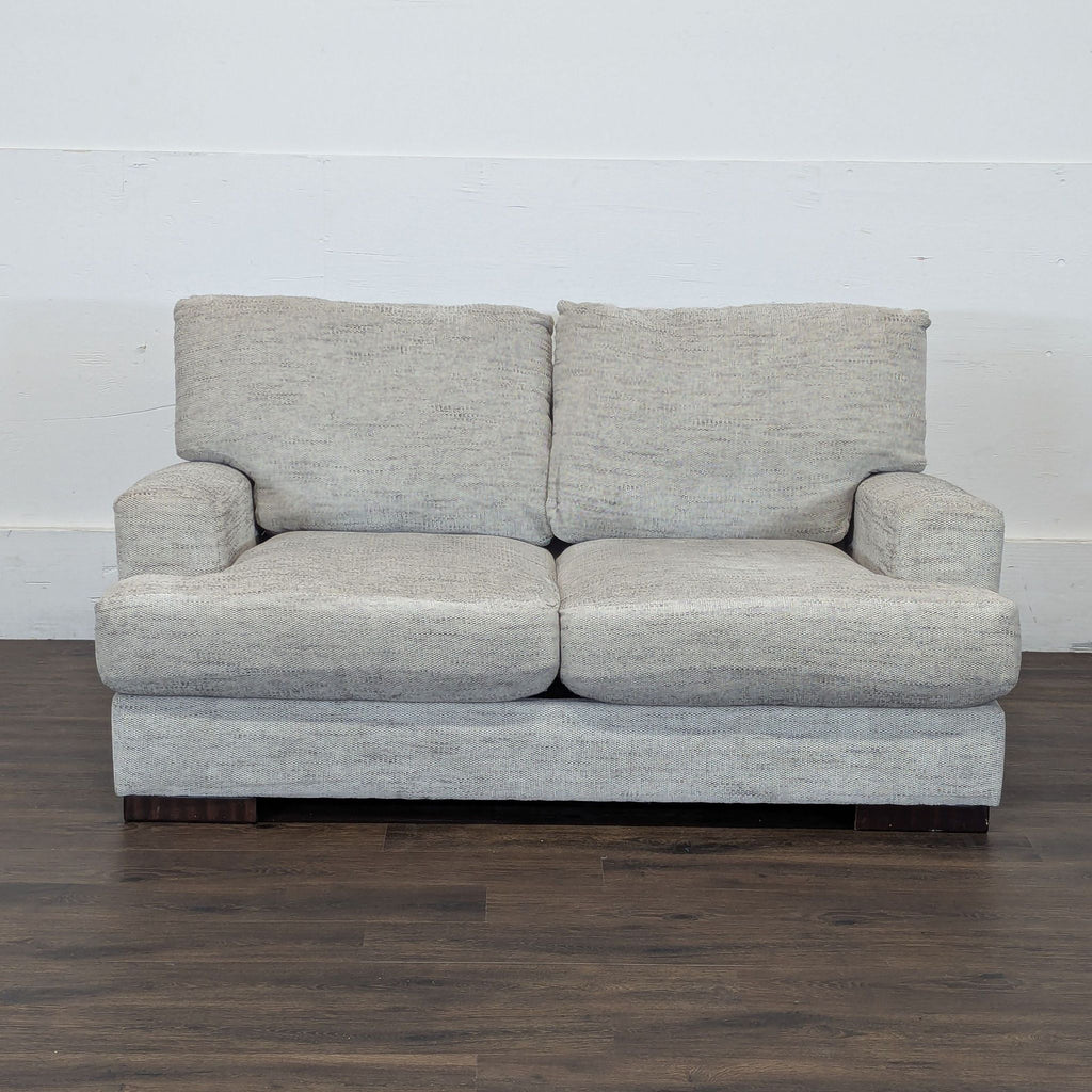3. Reperch light gray loveseat with plush cushions and armrests, shown against a plain white wall and wood floor.