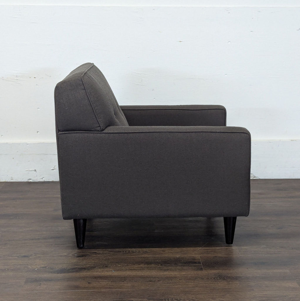 3. Side profile of a gray Reperch lounge chair, highlighting its boxy form and tapered legs.