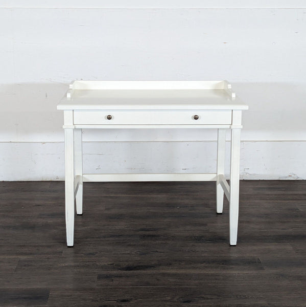 1. White Reperch writing desk with single drawer and raised back edges, seen against a wood floor and white wall.