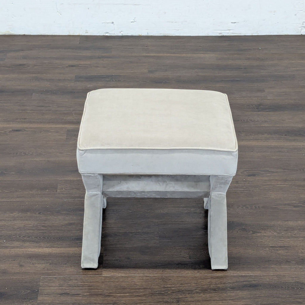 2. Top-down view of a Reperch cushioned grey ottoman with rectangular seat and soft fabric finish.