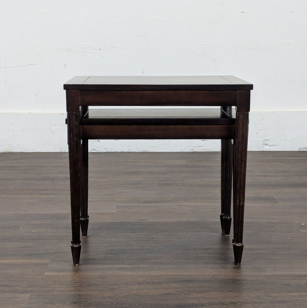 1. Set of two dark wood nesting side tables by Reperch, shown stacked on a hardwood floor.