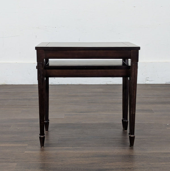 1. Set of two dark wood nesting side tables by Reperch, shown stacked on a hardwood floor.