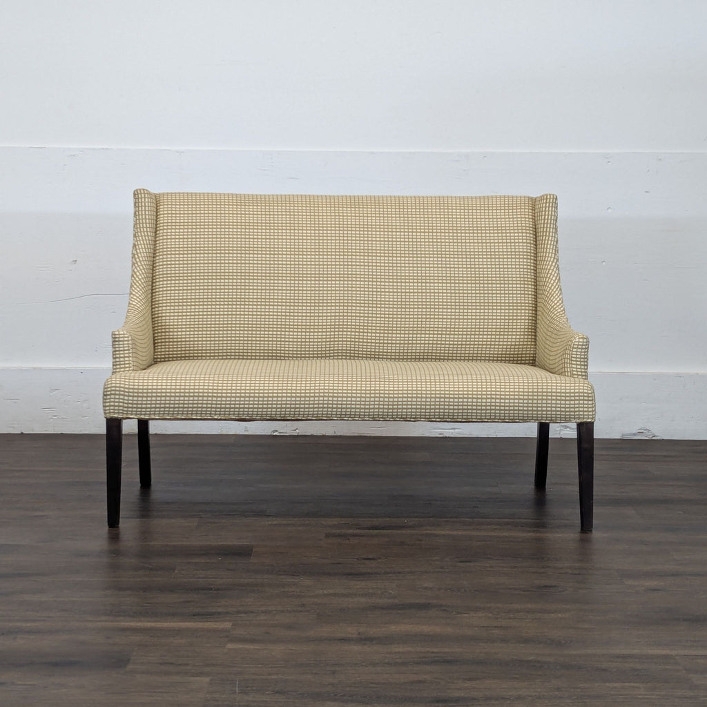 Front view of a Reperch bench with patterned beige upholstery and dark wooden legs, placed on a wooden floor.  
