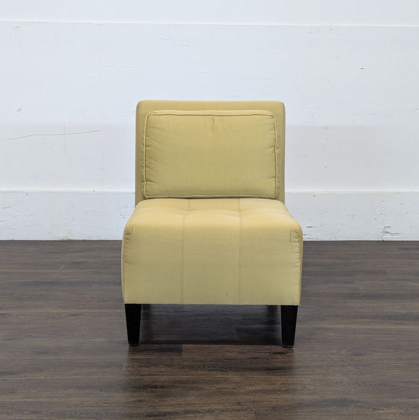 1. Front view of a modern Reperch lounge chair in light yellow upholstery with black legs on a wooden floor.
