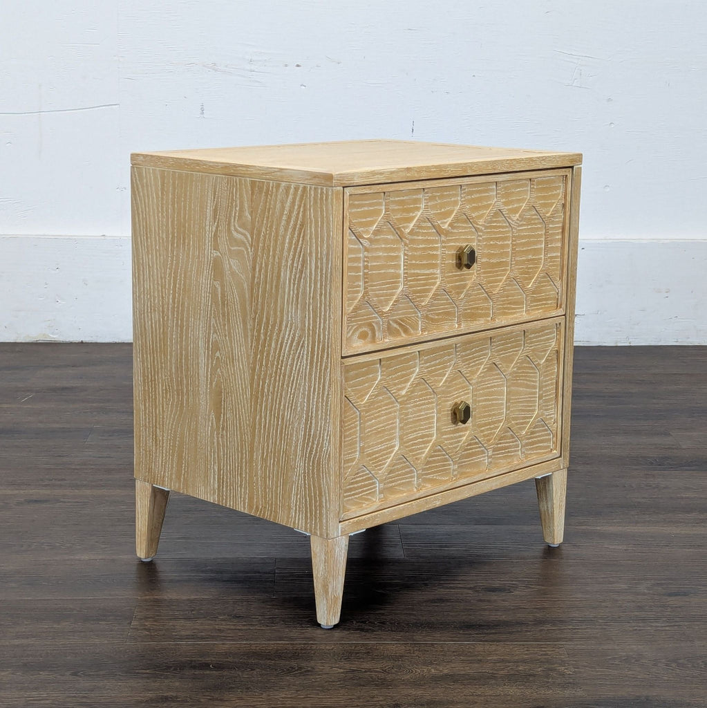 2. Angled view of a Reperch side table showing two drawers with a carved geometric design, in light wood.