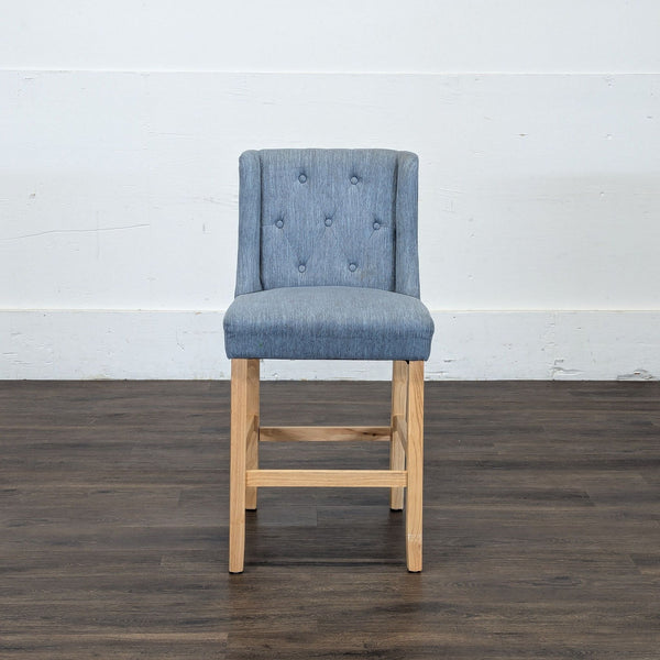 1. Reperch stool with blue tufted fabric backrest and seat, and light wooden legs, shown from the front.
