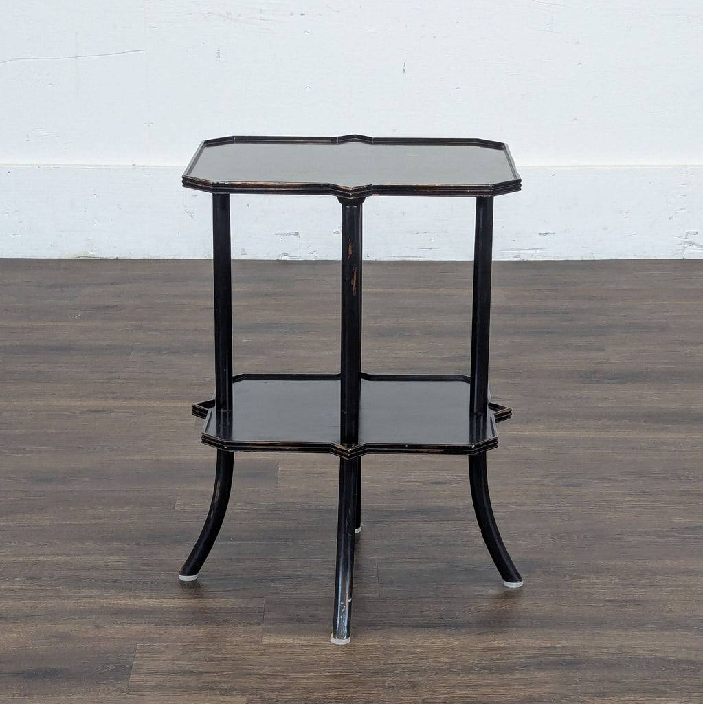1. Black two-tier Reperch side table with curved legs and scalloped edges, shown on a wood floor.