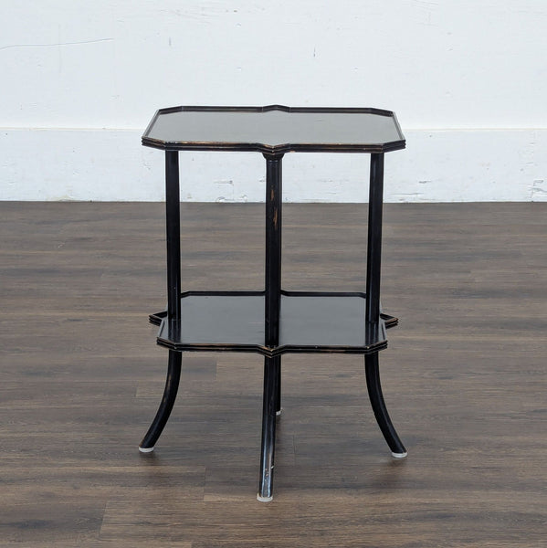 1. Black two-tier Reperch side table with curved legs and scalloped edges, shown on a wood floor.