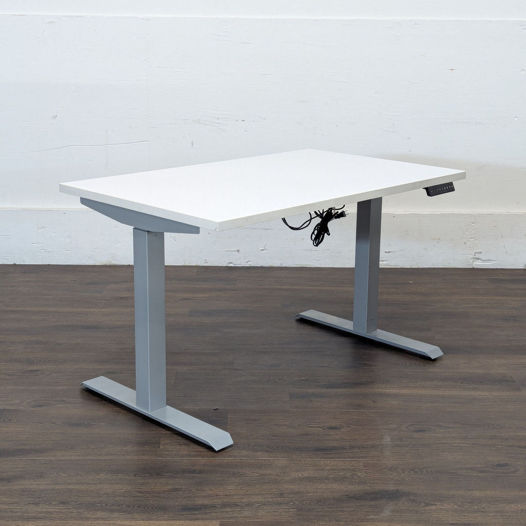 3. Side angle view of a Reperch desk with a sleek white top and modern metal legs, power cords underneath.