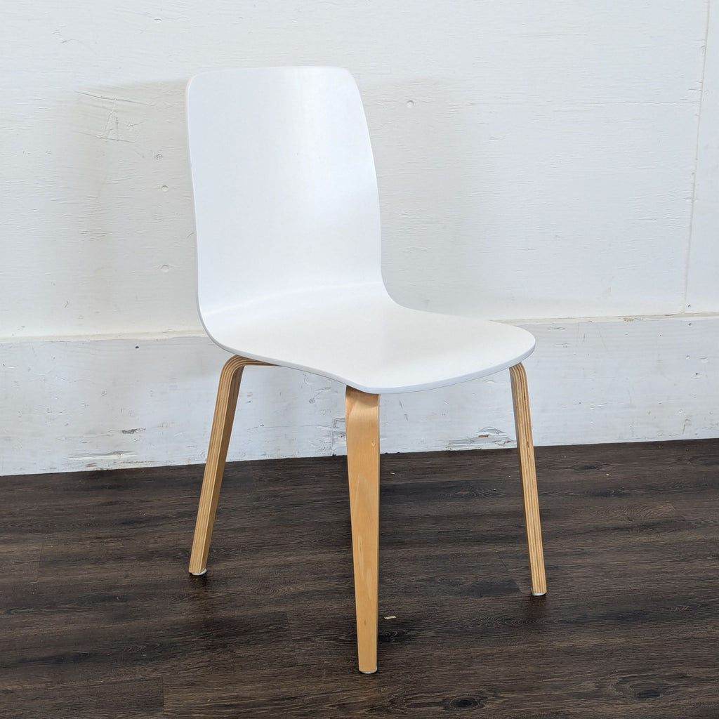 Single modern Reperch dining chair with white curved seat and natural wood legs on a dark floor.