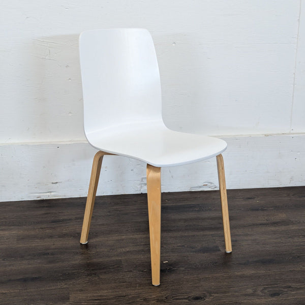 Single modern Reperch dining chair with white curved seat and natural wood legs on a dark floor.