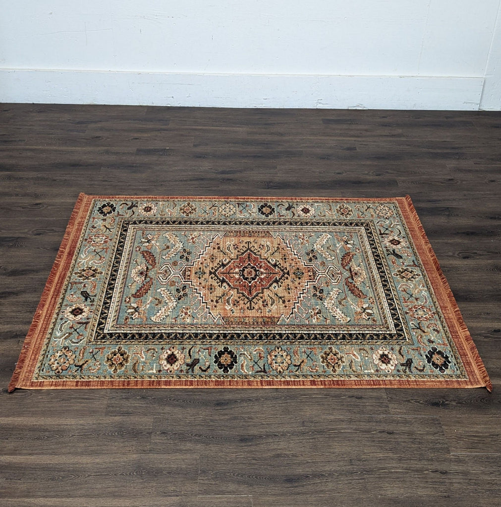 3. Patterned Reperch rug in blue, rust, and beige, featuring detailed borders and medallion, laid on wooden floor.