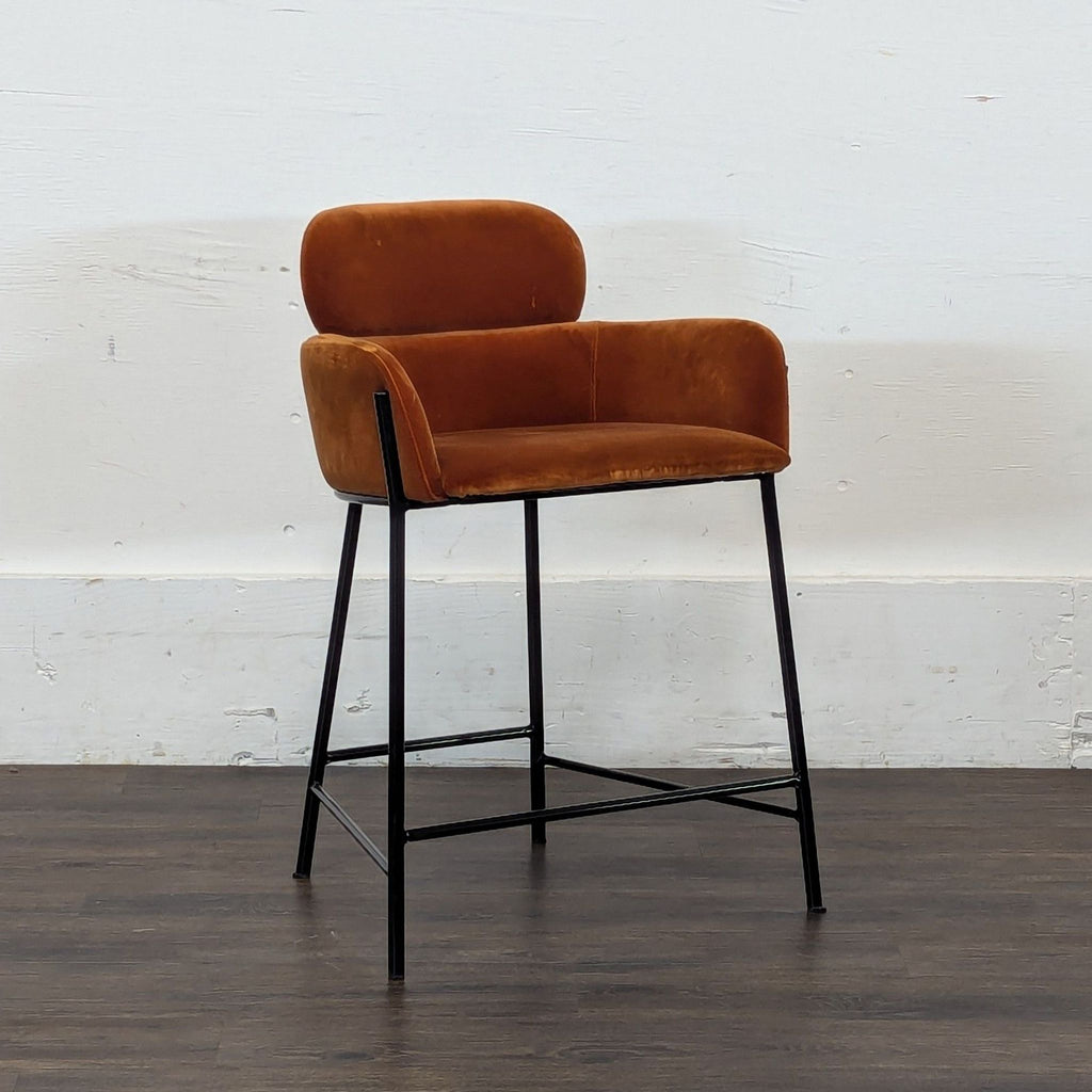 3. 4x chairs brand orange velvet armrest stool, angled view, black metal frame, against a white wall background.