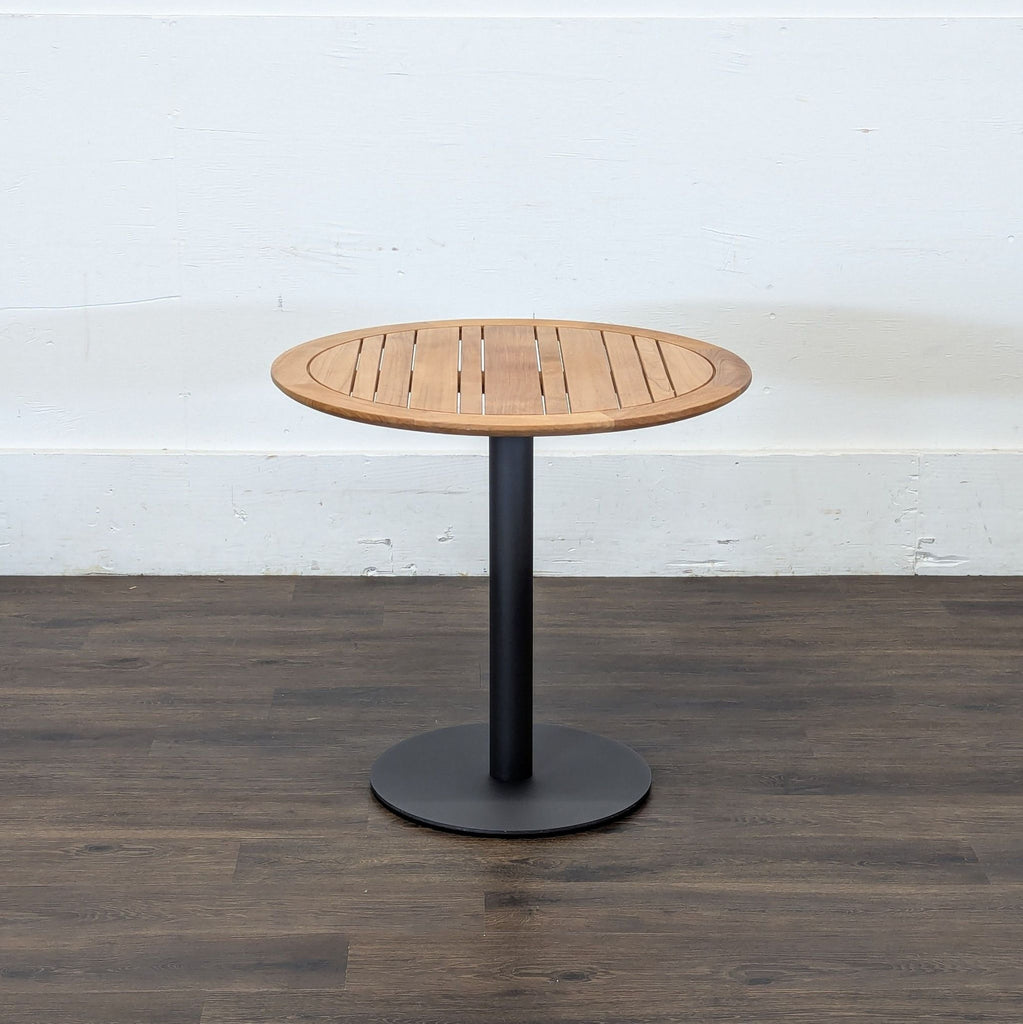 3. Side view of Reperch console table, featuring slatted wooden round top and black metal pedestal base.