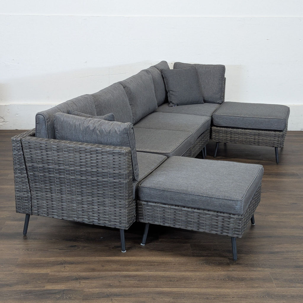 3. Angled view of a rattan outdoor seating set with grey cushions on a wooden floor, category: Sets.