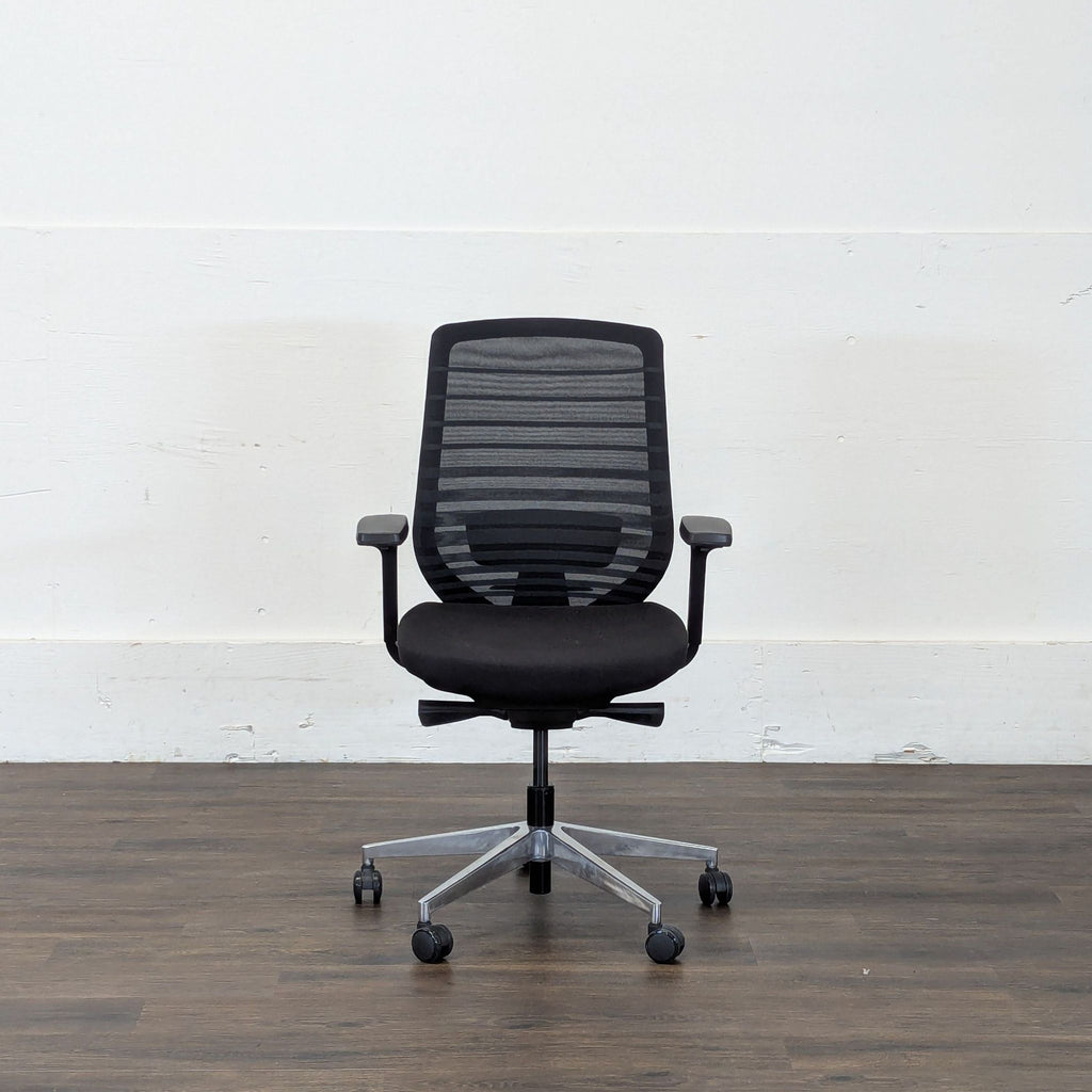 2. Ergonomic Reperch chair with black mesh back and cushioned seat, centered on a wood floor background.