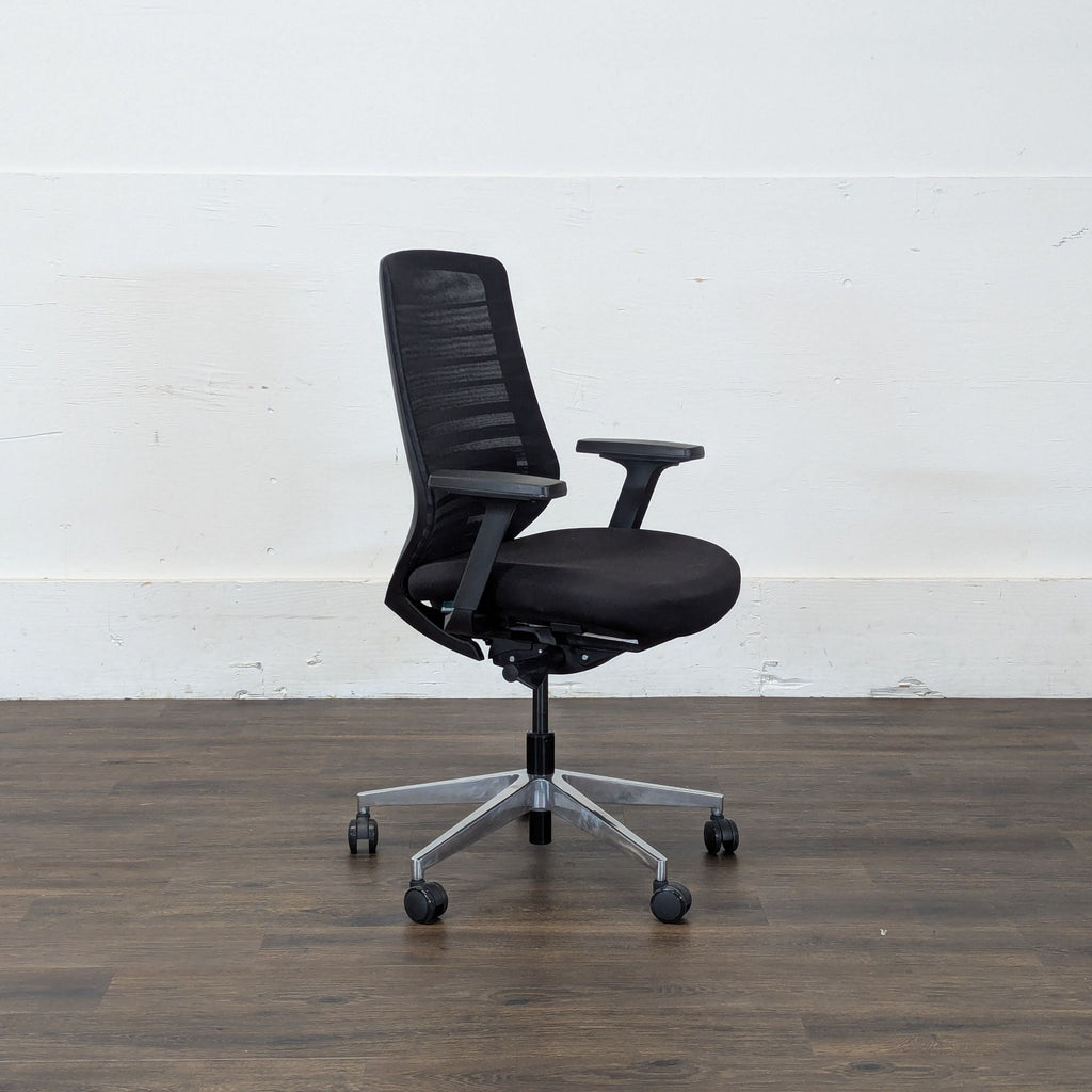 3. Side view of a Reperch black office chair with mesh back, armrests, and rolling base on a wooden floor.
