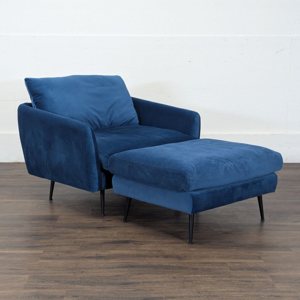 3. Side view of a blue lounge chair with ottoman, showing slim black legs and plush cushions.  