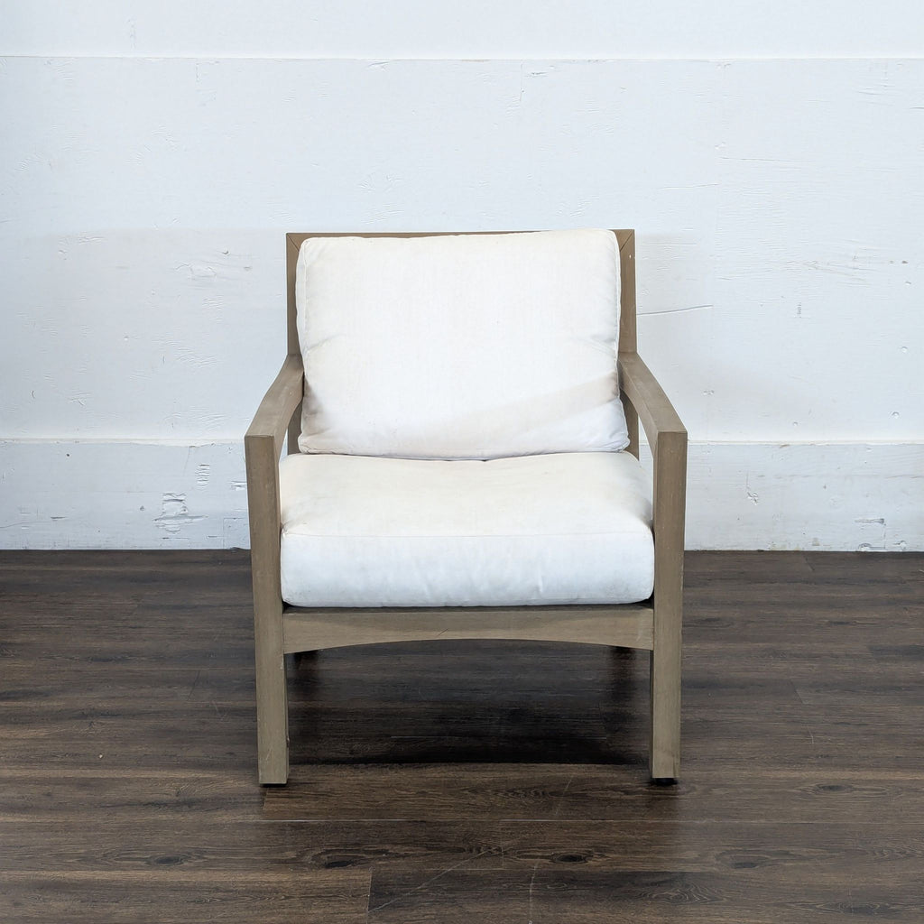 2. Pottery Barn chair with a wooden frame and white cushions, set against a plain white wall on wood flooring.