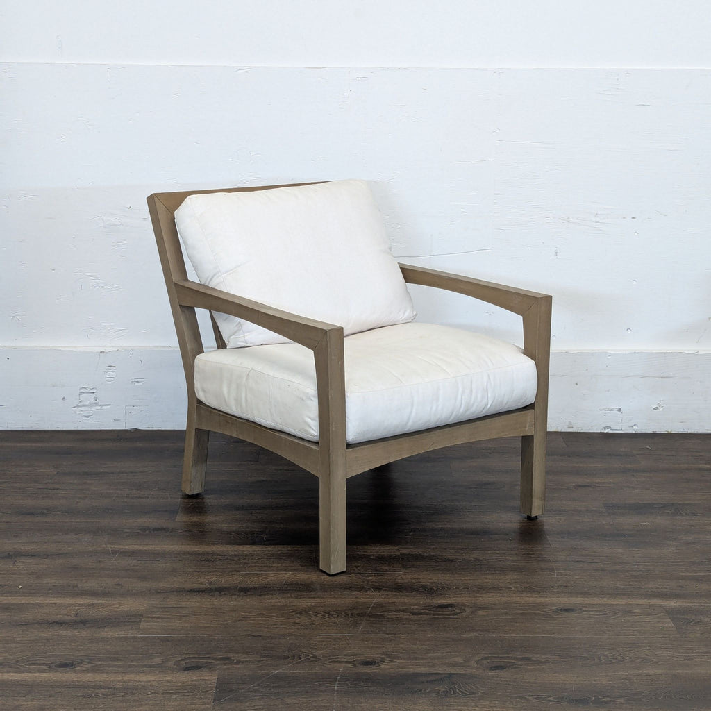 3. Angled view of a Pottery Barn chair showing wooden arms and white cushions, displayed on a dark wood floor.