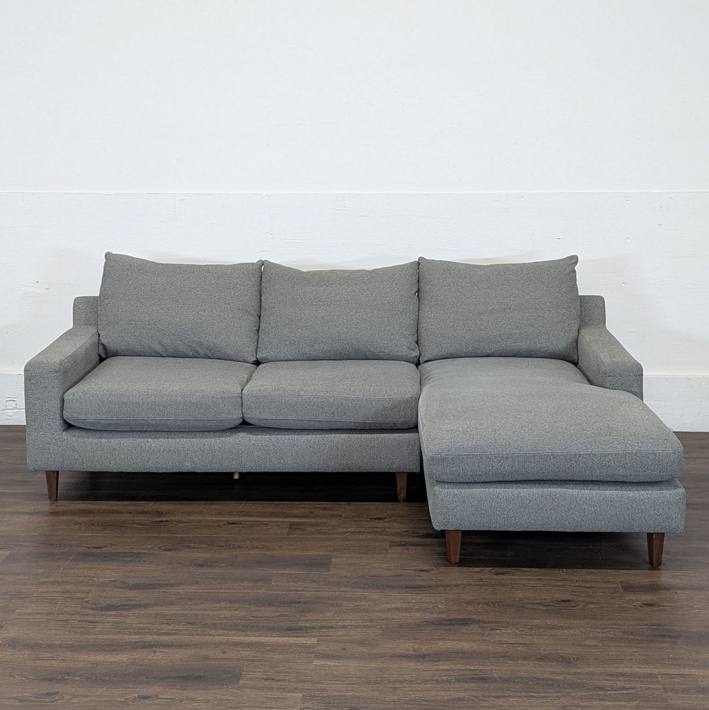 2. Gray Sloan sectional by Interior Define with left chaise, heather fabric, and wooden legs against a white wall.  
