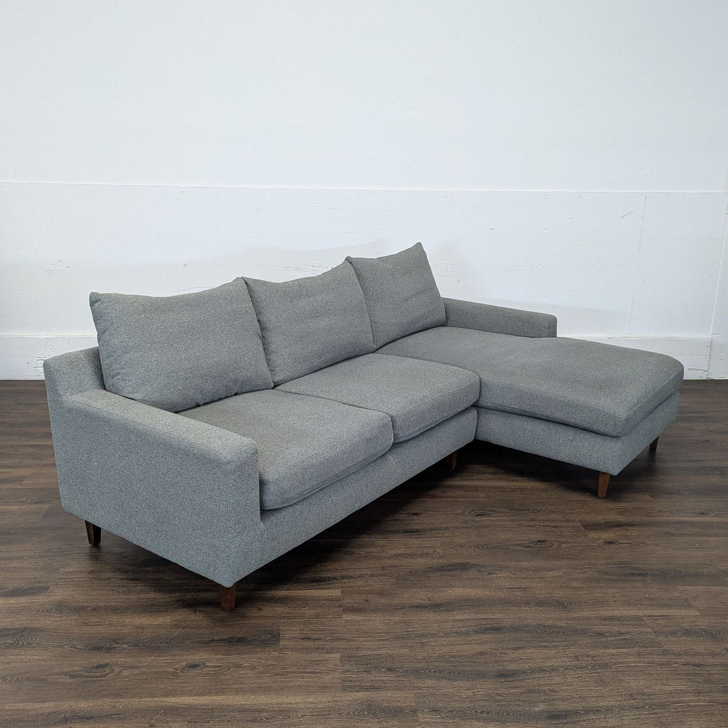 3. Angled view of Interior Define Sloan sectional, left chaise, heather fabric, and clean lines on a wood floor.