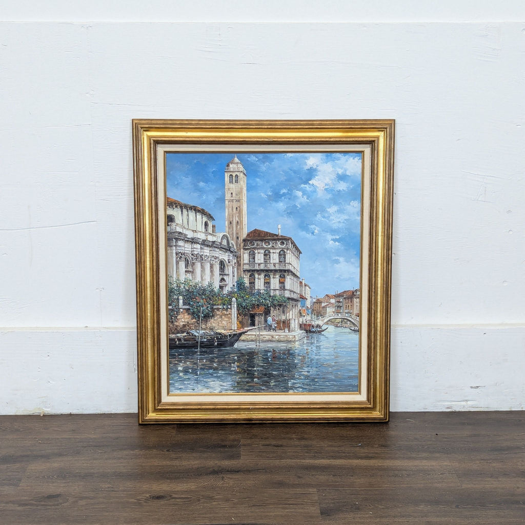 2. Canal cityscape oil painting in ornate gold frame, featuring buildings, a bell tower, and serene water.