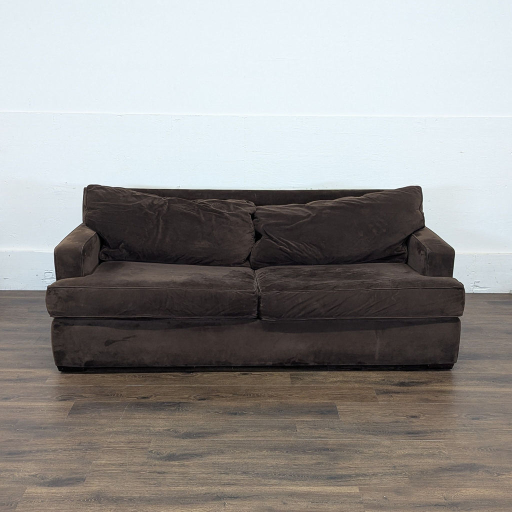 2. Front view of a brown Macy’s 3-seat sofa with plush cushions, on a wood floor in a plain room.