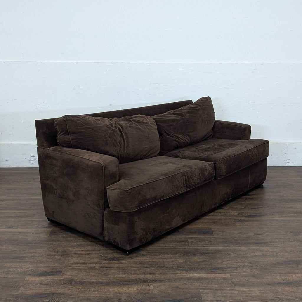 3. Angled side view of a Macy’s 3-seat brown sofa, showing soft cushions and square armrests on wood flooring.