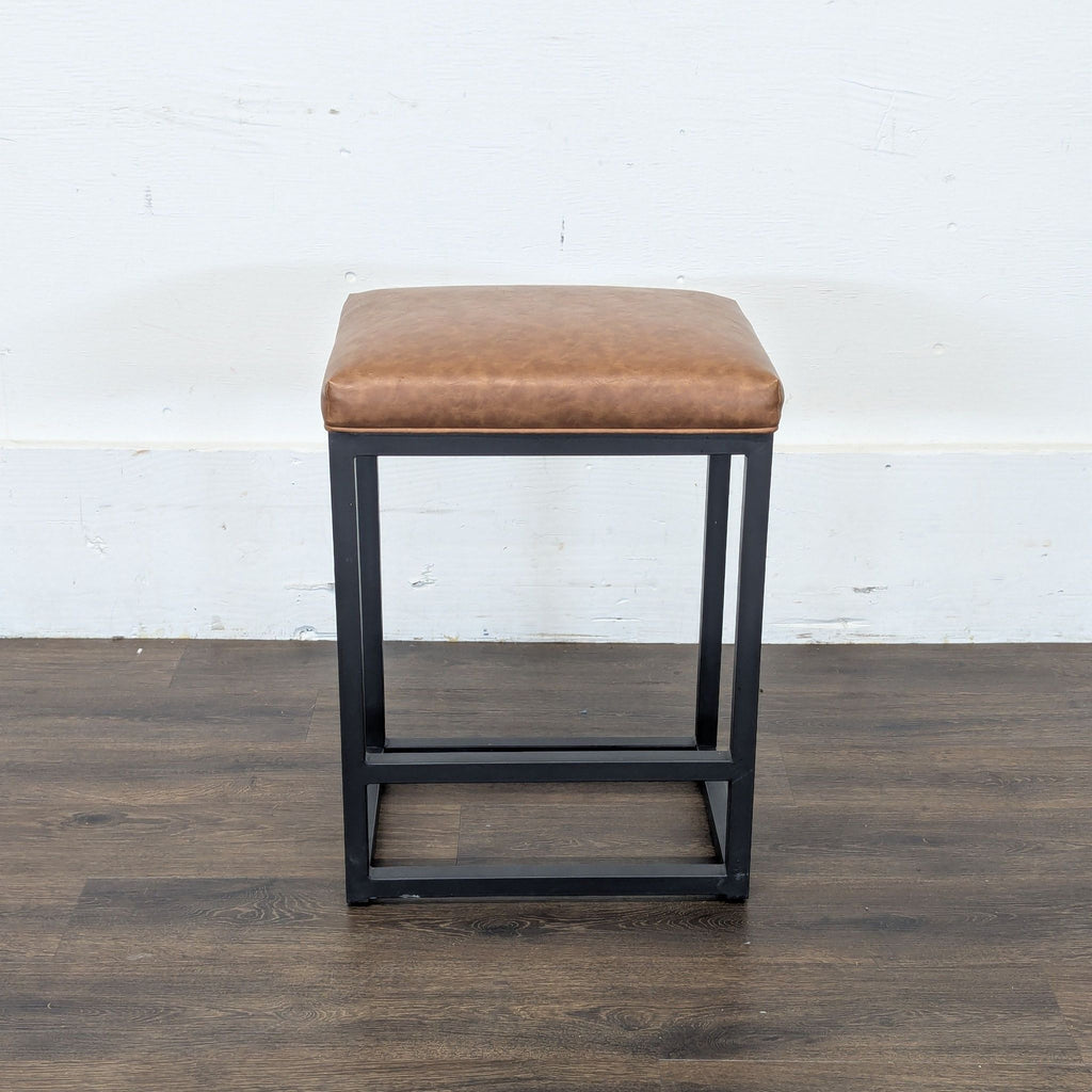 Single Reperch stool featuring a brown padded seat and black square metal base on dark wood floor.