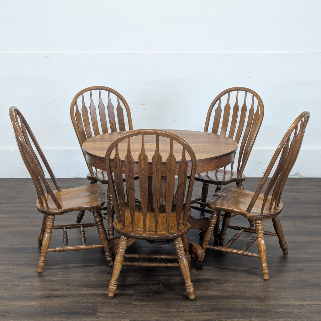 3. Reperch dining set displayed in a studio: round table and six wooden chairs on a dark wood floor.