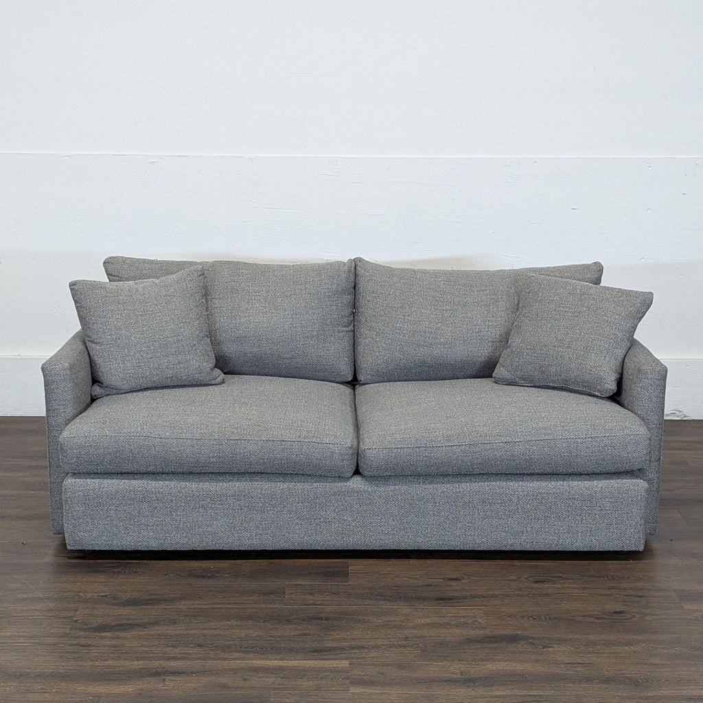 3. Crate and Barrel 3-seat couch in gray fabric, neatly styled with pillows, on a dark wooden floor.