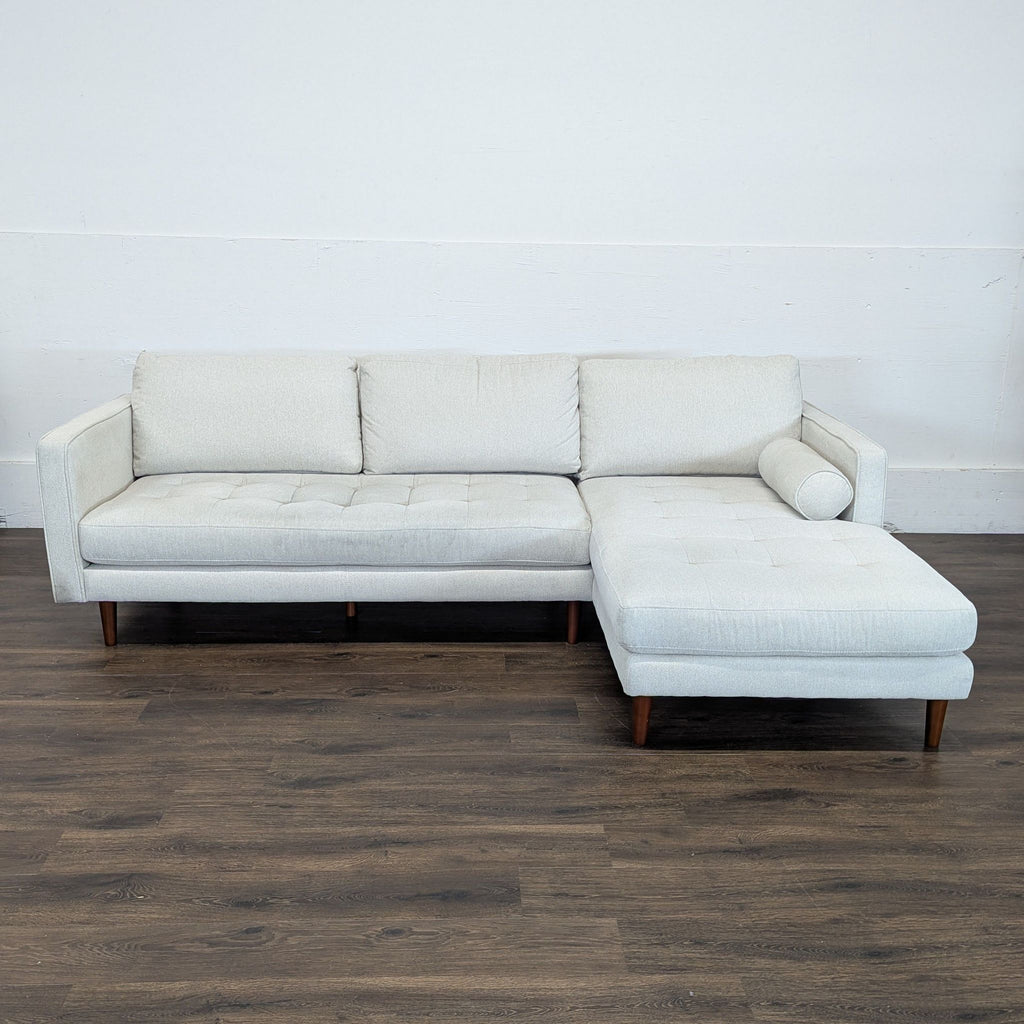 3. Minimalist LUKAS OPTICAL sectional couch with right-facing chaise, button-tufted seats, and wooden legs on wood floor.