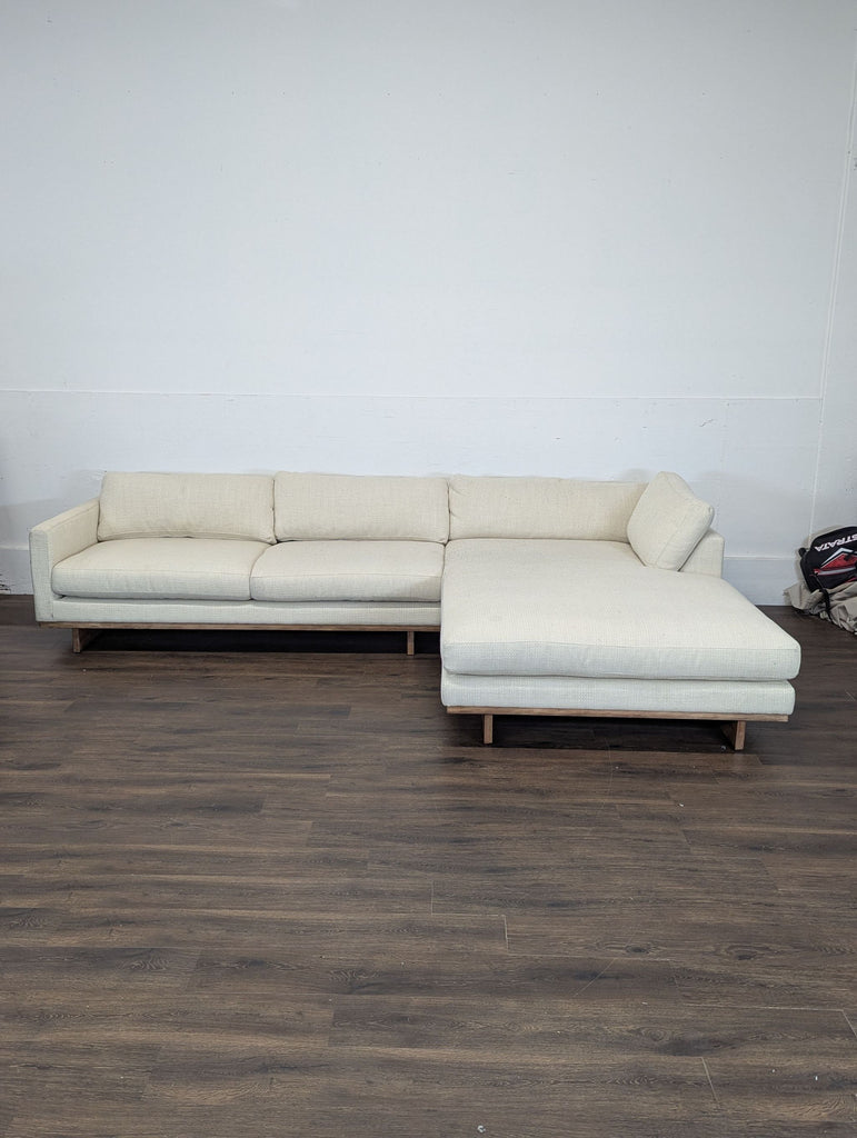 2. Cream Reperch sectional sofa from the Sectional category, shown against a white wall on wood flooring.