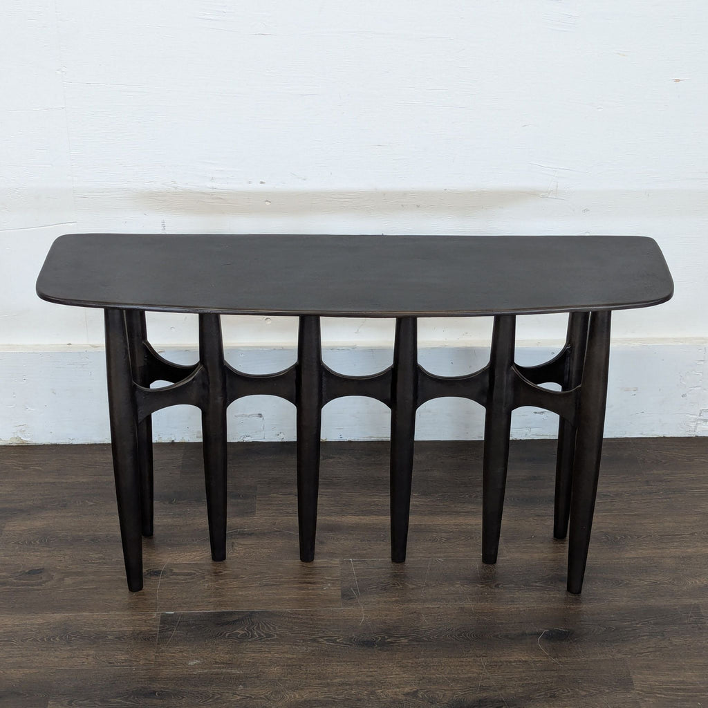 2. Sleek black side table by CB2, featuring six slender, arched legs and a smooth, curved top.