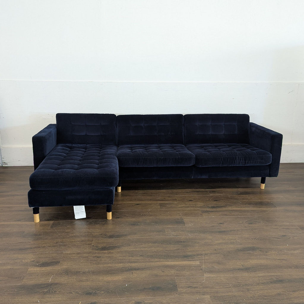 1. Dark blue sectional sofa from IKEA with tufted cushions and wooden legs, set on a wooden floor.