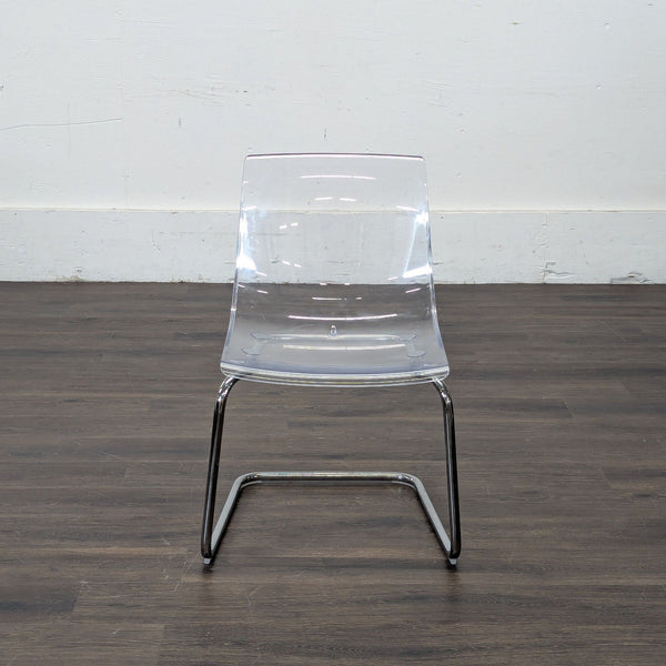 1. Clear acrylic dining chair with chrome legs from Ikea, shown on dark wood flooring against a white wall.