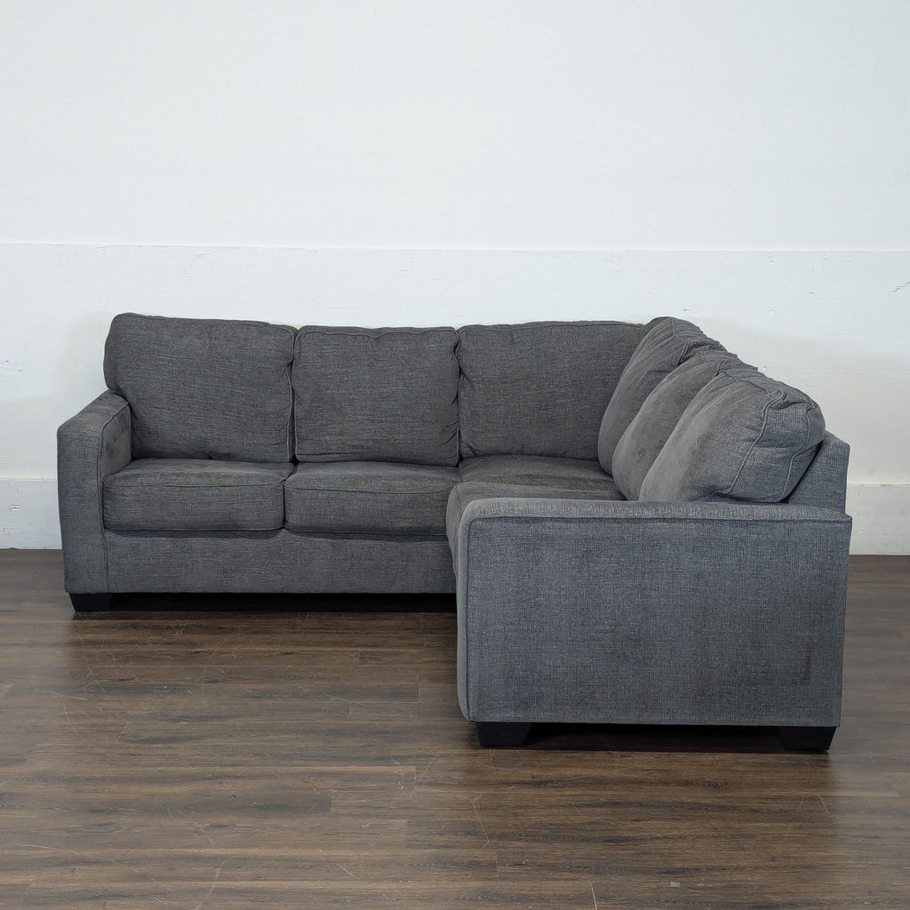 1. Dark gray Ashley Furniture sectional sofa with three-seat configuration, set on wooden floor against white wall.