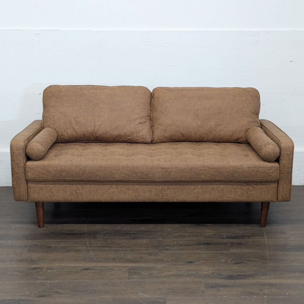 Brown Avantio 3-seat sofa with plush cushions and cylindrical arm pillows, shown against a white wall.