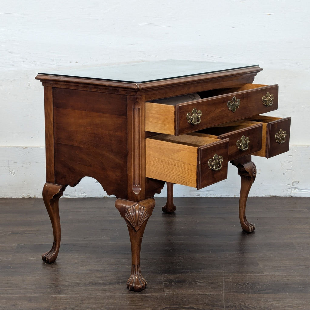 Vintage credenza featuring carved cabriole legs, three drawers with brass hardware, and a glass-covered top.