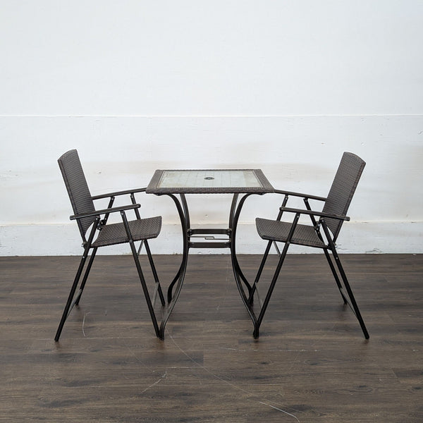 1. Two brown wicker chairs and a square glass-top table set on a dark wooden floor, viewed from the side.