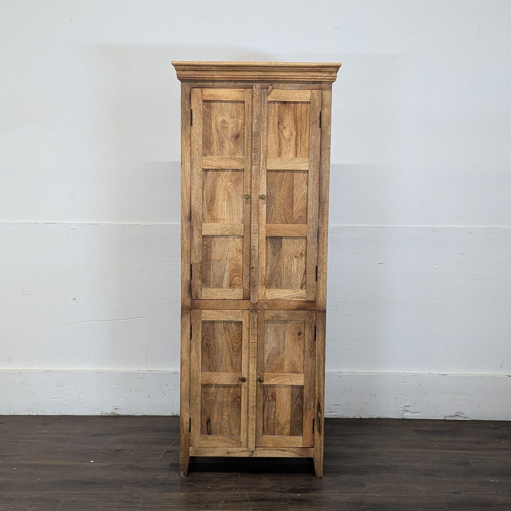 2. Tall wooden cabinet with closed paneled doors, standing on a dark floor against a plain wall.