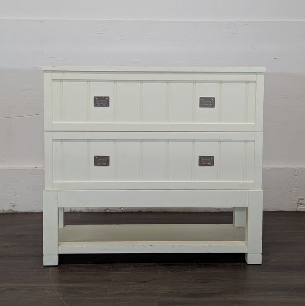 1. White sideboard with two panel-front drawers and lower shelf, metal handles, on dark wooden floor.