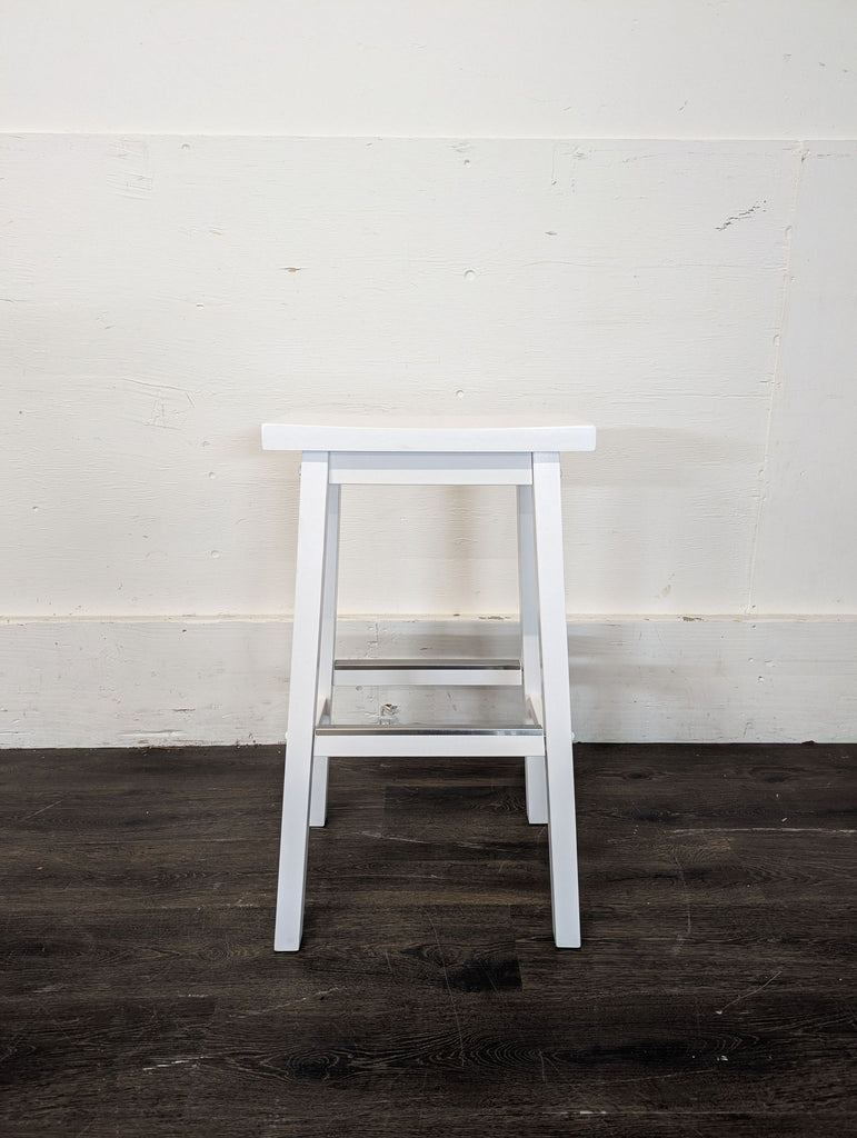 2. A single white wooden stool with a rectangular seat and footrest, standing on a dark floor.