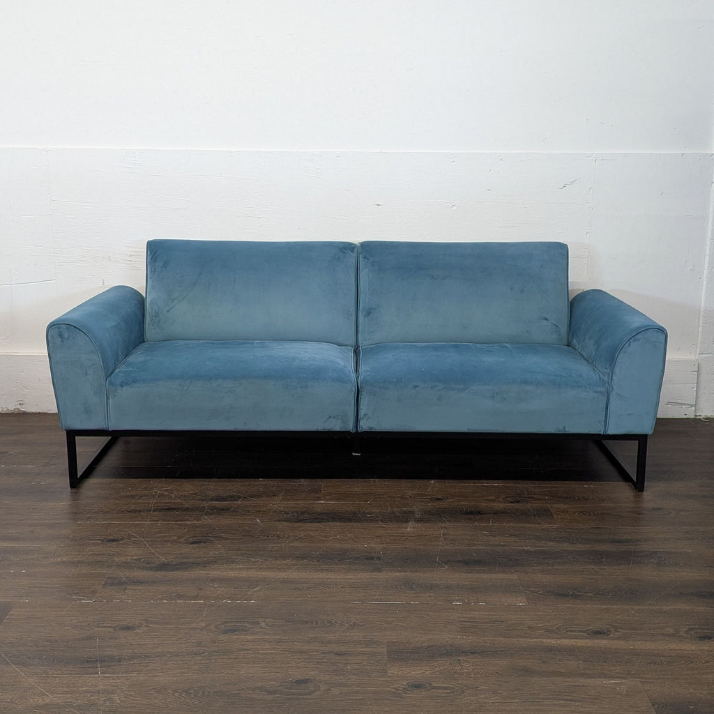 Three-seat teal velvet sofa convertible to a full-size bed.