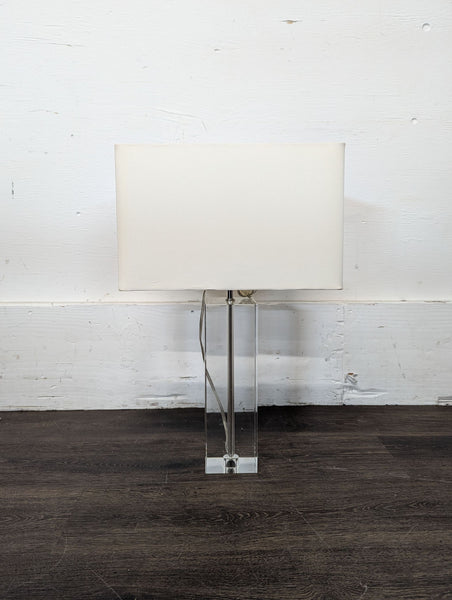 1. Modern table lamp with a rectangular white shade and a clear acrylic base, placed on a dark floor.