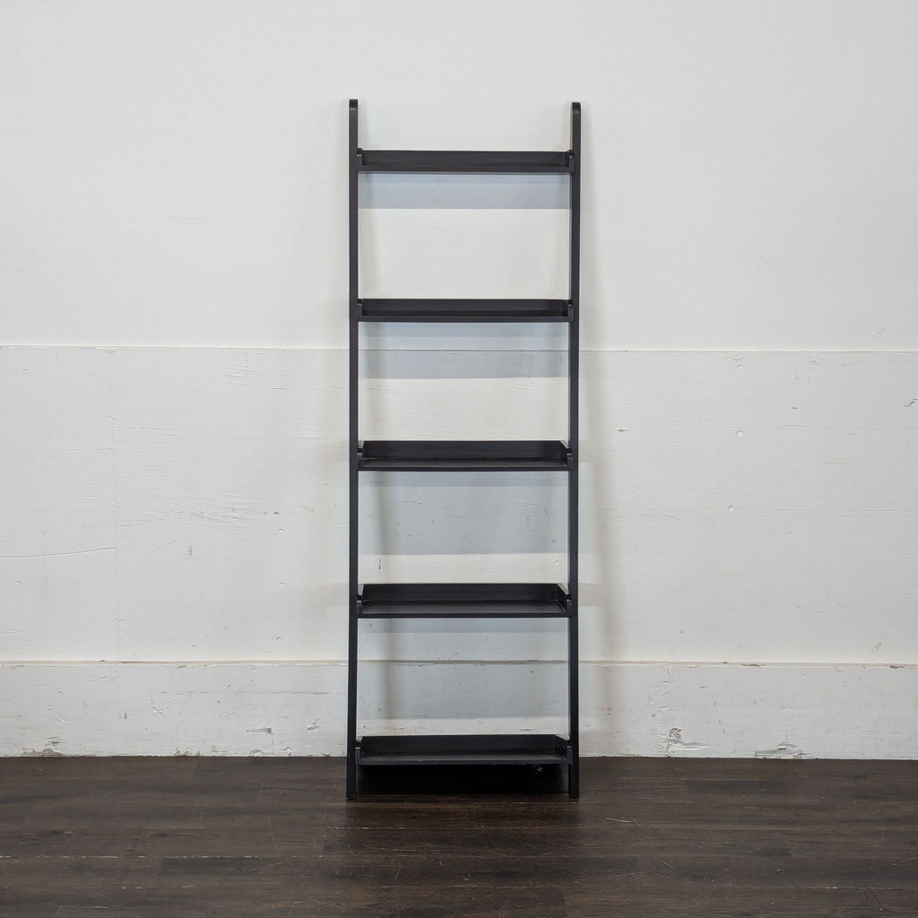 2. Tall, dark-finished bookshelf filled with assorted books and plants, standing against a white wall.