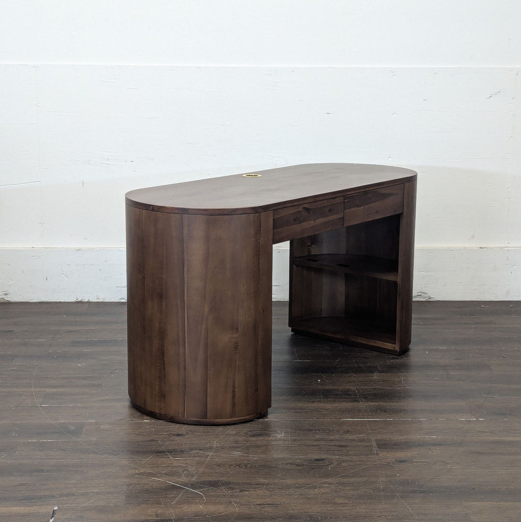 3. Sleek wooden desk with curved sides, open shelves, and a cable hole, viewed from an angle indoors.