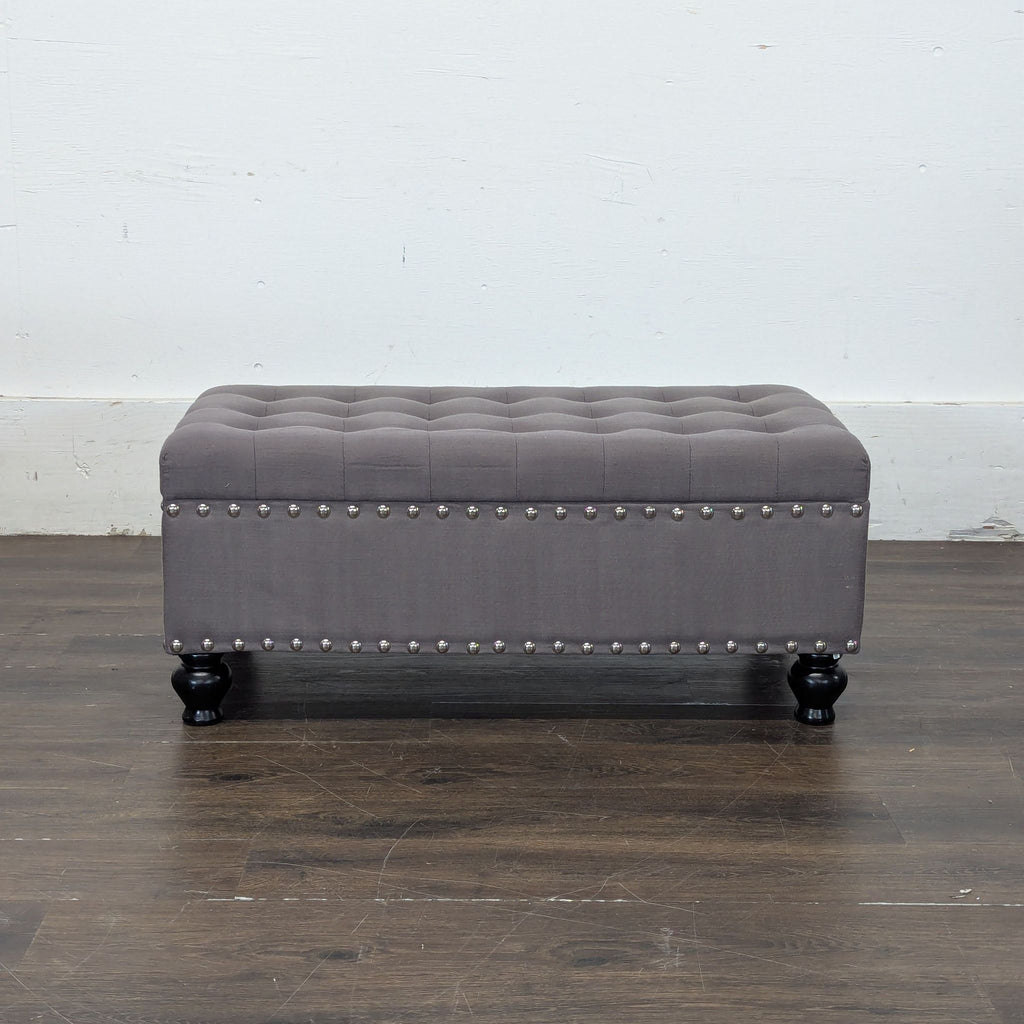 1. Gray tufted ottoman bench with nailhead trim and dark wooden legs, from Marshall’s, on a wood floor.