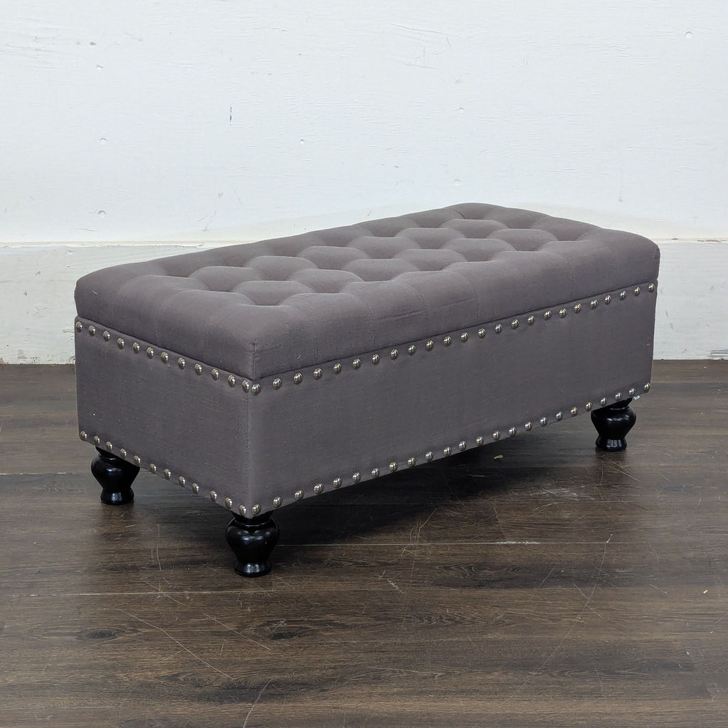 2. Marshall’s gray upholstered ottoman with studded accents and turned black legs, category: Stools, Ottomans & Benches.